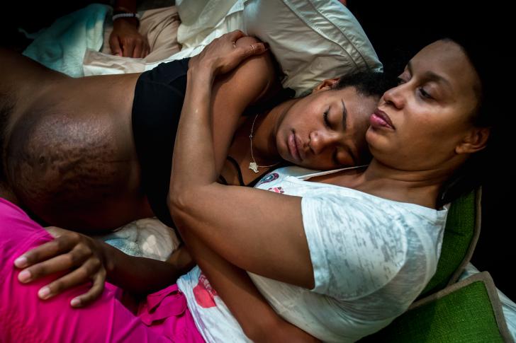 two women laying on a bed