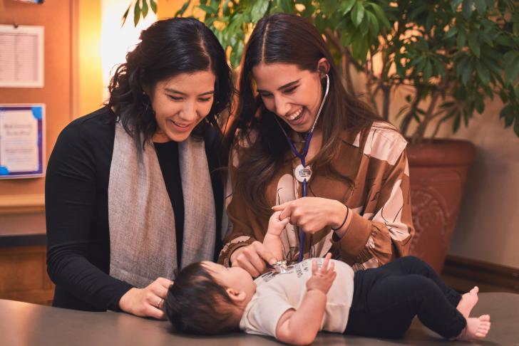 two women performing a health exam on a baby