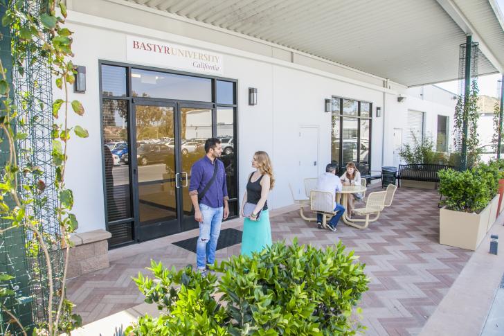 two students standing outside on patio talking to each other