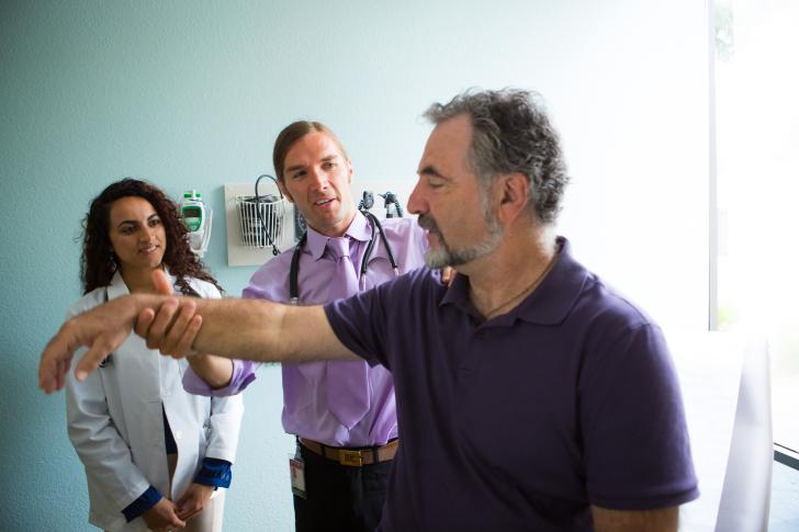 two doctors with one patient examining arm