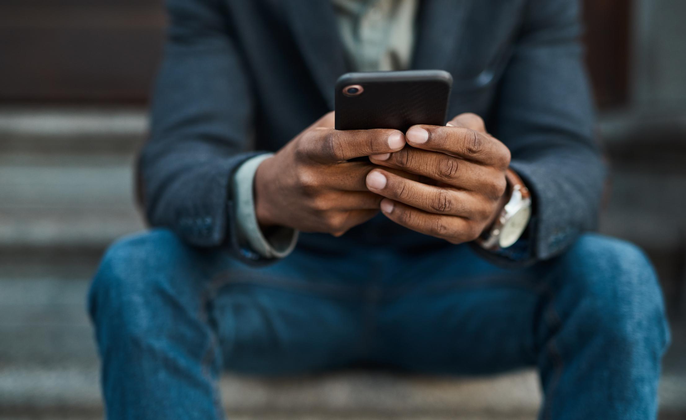 close up of person looking at cell phone sitting on steps