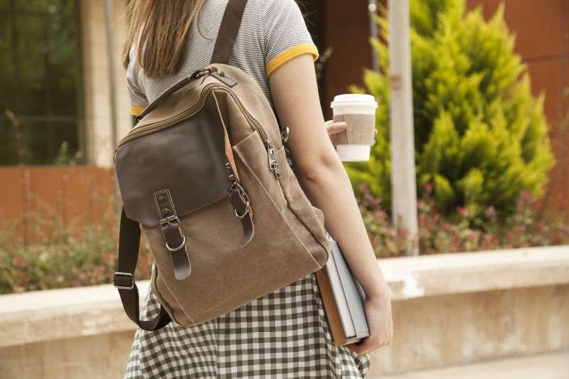 student walking with backpack and cup of coffee